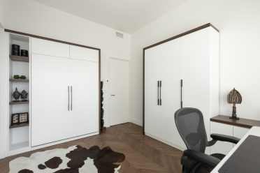 Structure de lit escamotable contemporain blanc avec tapis de vache et chaise de bureau.