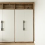 Chambre moderne avec lit escamotable blanc intégré dans un placard en bois, entouré d'étagères avec éclairages encastrés.