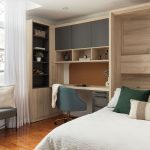 Chambre moderne avec lit escamotable intégré dans un placard en bois, entouré d'étagères et d'un bureau avec éclairages encastrés.