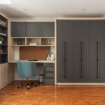 Chambre moderne avec lit escamotable intégré dans un placard en bois, entouré d'étagères et d'un bureau avec éclairages encastrés.