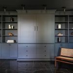 Chambre moderne avec lit escamotable intégré dans un placard en bois bleu, entouré d'étagères.