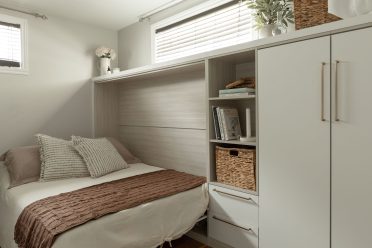 Mobilier mural sur mesure en fini pâle, conçu par Limuro, intégrant un lit escamotable latéral entièrement dissimulé et des rangements fermés et ouverts.