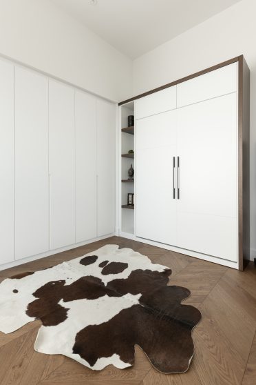 Bureau lumineux aménagé par Limuro avec lit escamotable sur mesure dissimulé dans un meuble mural blanc, rangement intégré et accents de bois foncé, combinant fonctionnalité et design épuré.