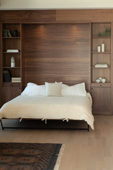 Lit escamotable Limuro en bois de noyer déployé, transformant le salon en chambre confortable. Un design épuré et chaleureux, pensé pour maximiser l’espace sans compromis sur le style.