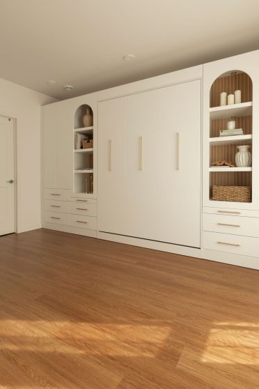 Lit mural escamotable Limuro fermé, intégré dans un mobilier sur mesure avec rangements, étagères décoratives et poignées dorées, conçu pour un aménagement fonctionnel et harmonieux.