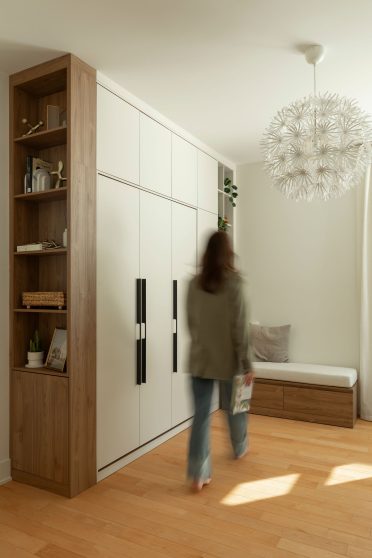 Lit mural escamotable Limuro fermé, intégré dans un mobilier sur mesure avec rangements, étagères décoratives et poignées dorées, conçu pour un aménagement fonctionnel et harmonieux.