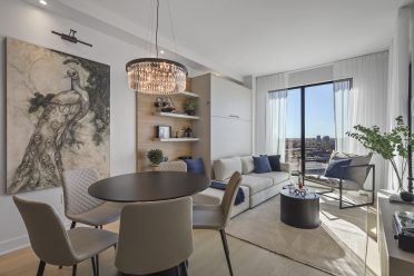 Espace de vie lumineux avec salle à manger et salon modernes, comprenant une table ronde, un canapé clair et une grande fenêtre offrant une vue extérieure.