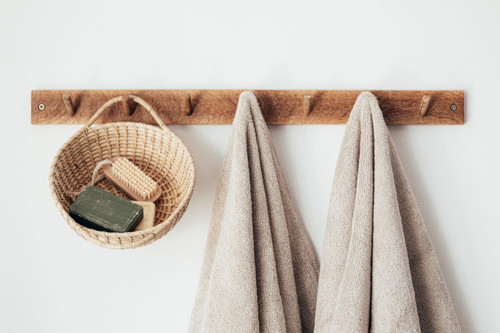 Astuce de rangement maison : crochets suspendent des serviettes et un panier sur un mur.
