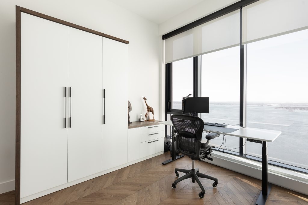 Structure de lit escamotable contemporain blanc avec rangement et bureau donnant sur une grande fenêtre.