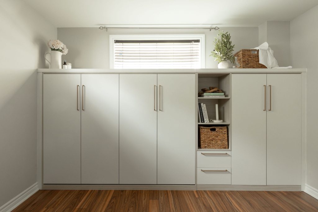 Mobilier mural sur mesure en fini pâle, conçu par Limuro, intégrant un lit escamotable latéral entièrement dissimulé et des rangements fermés et ouverts.