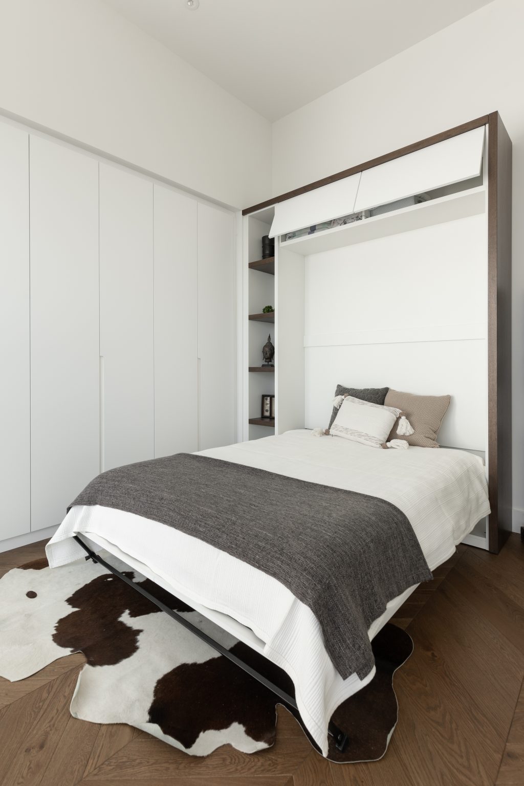 round-image static-image Bureau lumineux aménagé par Limuro avec lit escamotable sur mesure dissimulé dans un meuble mural blanc, rangement intégré et accents de bois foncé, combinant fonctionnalité et design épuré.
