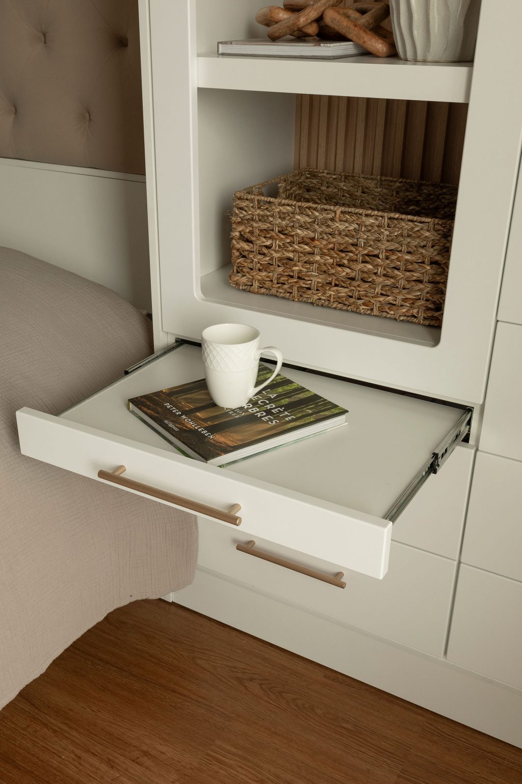 round-image static-image Vue rapprochée du tiroir escamotable intégré au mobilier Limuro, servant de table d’appoint pratique. Un livre et une tasse y reposent, illustrant la polyvalence et le confort du design sur mesure.