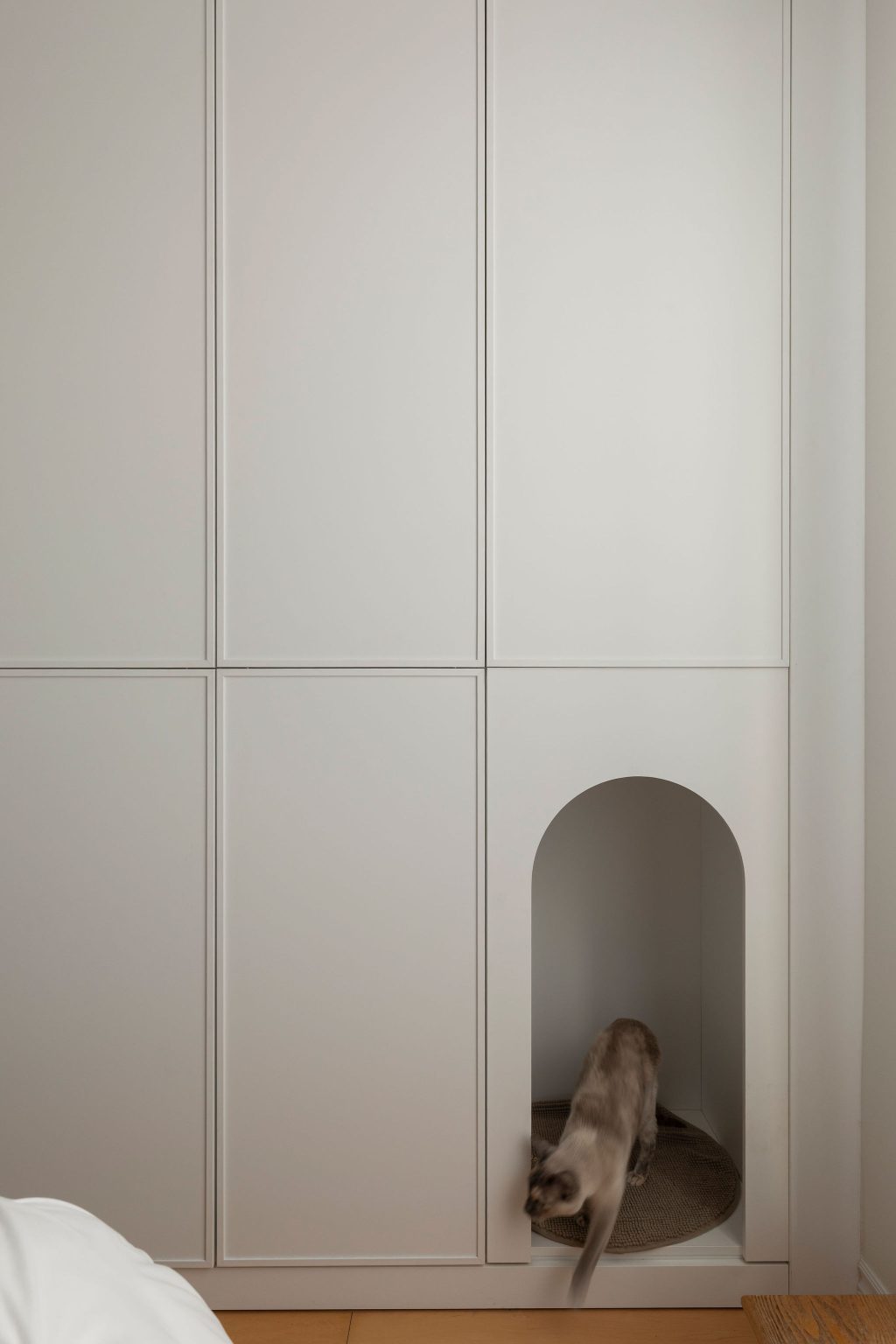 round-image static-image Mobilier sur mesure Limuro avec niche arrondie intégrée pour chat, dans une chambre minimaliste aux lignes épurées. Un aménagement fonctionnel et élégant adapté à la vie quotidienne.