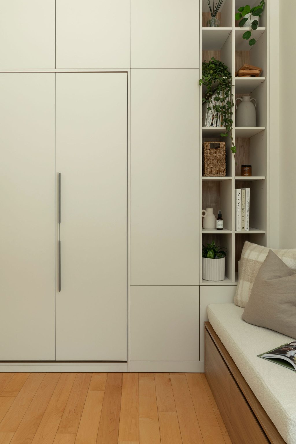 round-image static-image Vue rapprochée du mobilier sur mesure Limuro avec lit escamotable fermé, étagères intégrées et banquette. Les lignes épurées, les plantes et les textures naturelles créent un espace à la fois fonctionnel et apaisant.