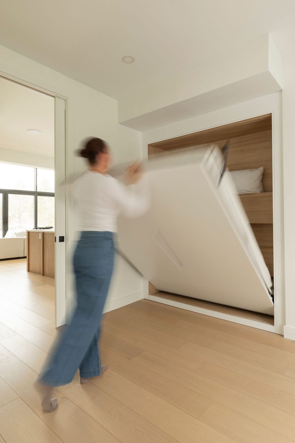 Personne en train de déployer un lit escamotable intégré dans un mur, illustrant un aménagement fonctionnel et gain de place.